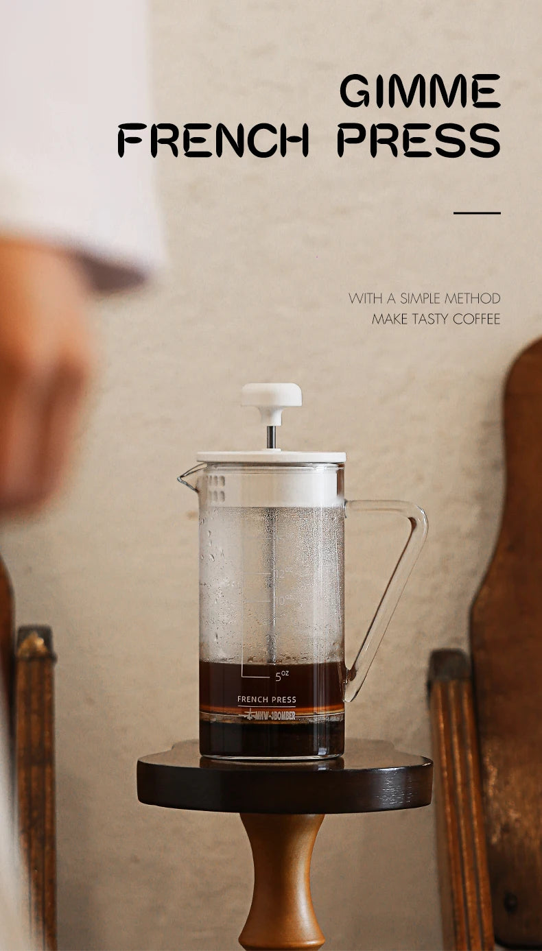 French press with coffee on a wooden stand against a neutral background