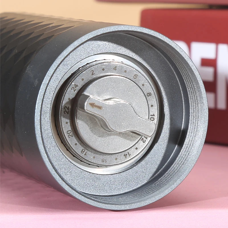 Close-up of a metal cylindrical object with measurement markings on a pink surface.