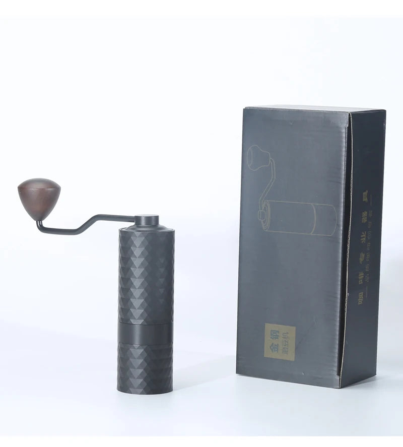 Black manual coffee grinder with textured design next to its packaging on a white background