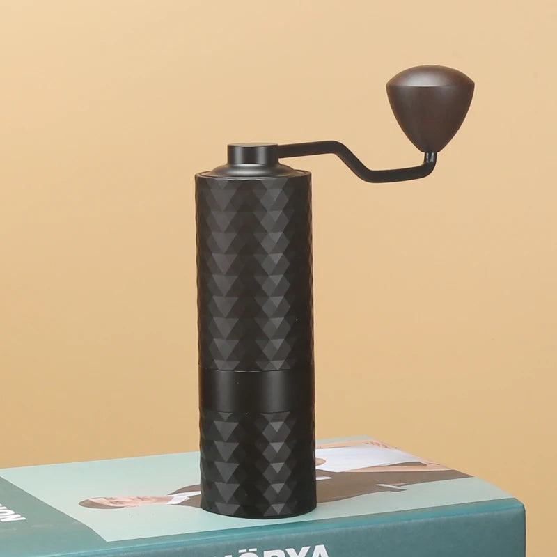 Black manual coffee grinder on a magazine with a beige background