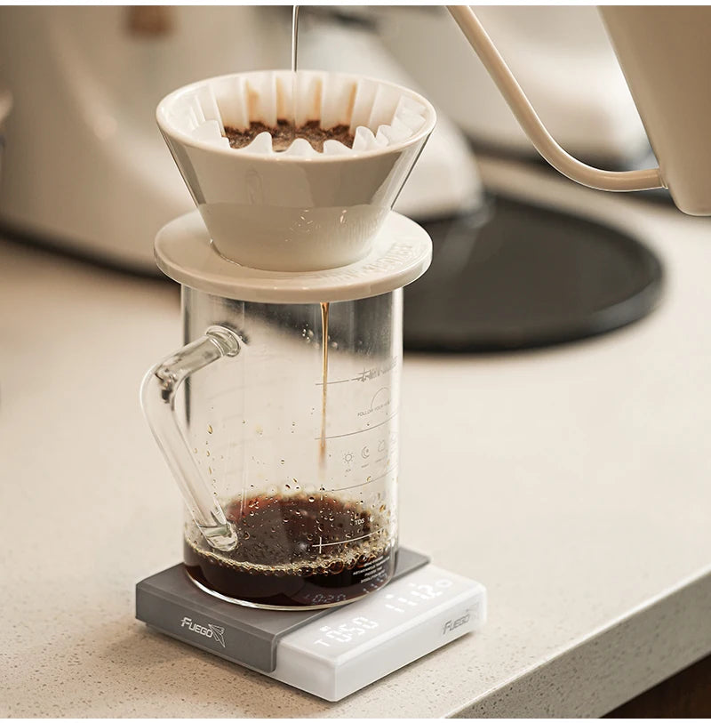 Coffee brewing process using a glass carafe and white paper filter on a kitchen counter.