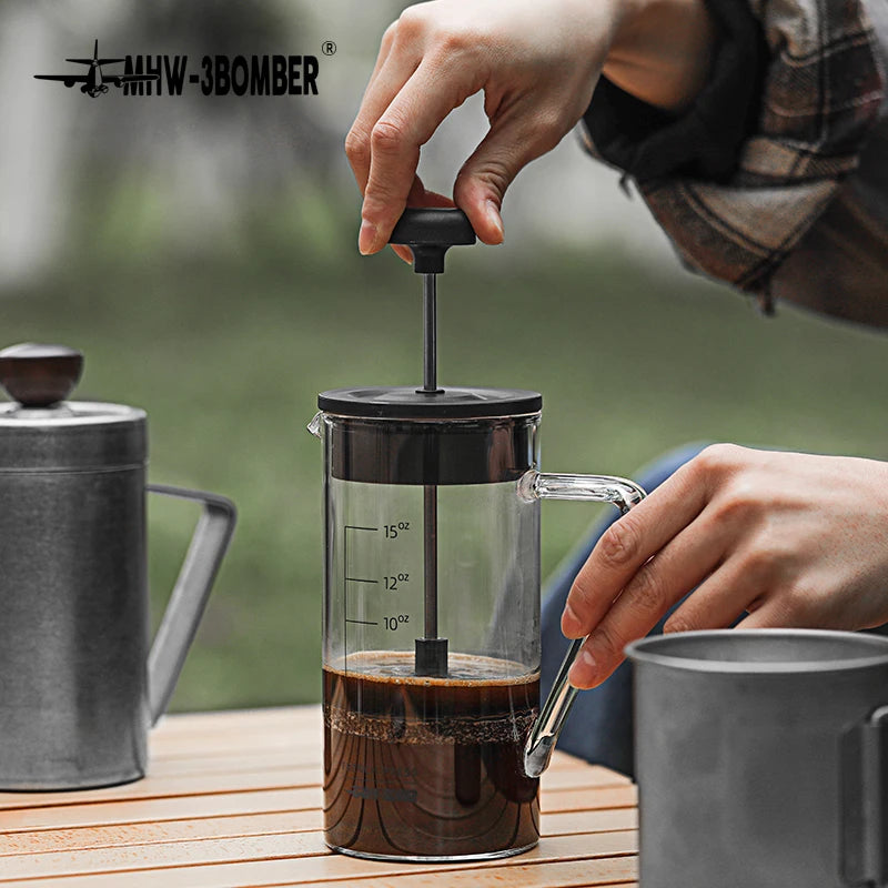 Person using a French press to make coffee with a blurred background