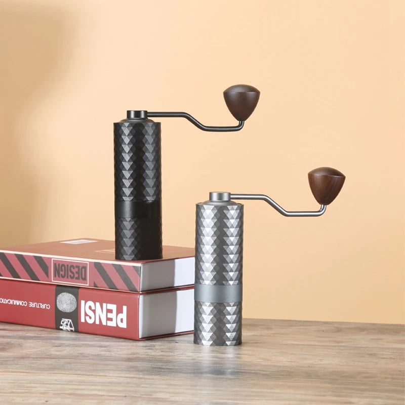Two manual coffee grinders on a wooden surface with a beige background